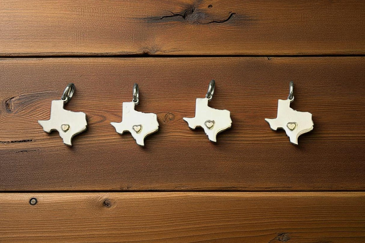 Four Texas-shaped pendants with heart cutouts on a wooden surface