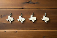 Thumbnail for Four Texas-shaped pendants with heart cutouts on a wooden surface