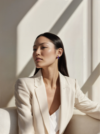 Thumbnail for Woman in a white blazer sitting against a light background wearing amethyst dangle earrings