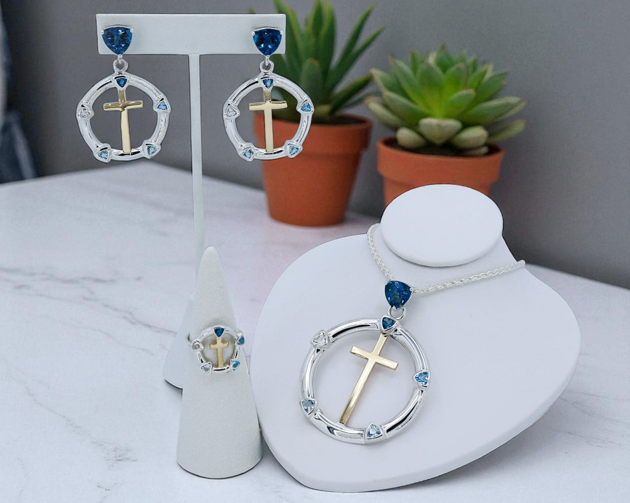 Jewelry set with cross designs on a white surface with plants in the background