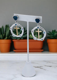 Thumbnail for Earrings with crosses on a white stand with plants in the background
